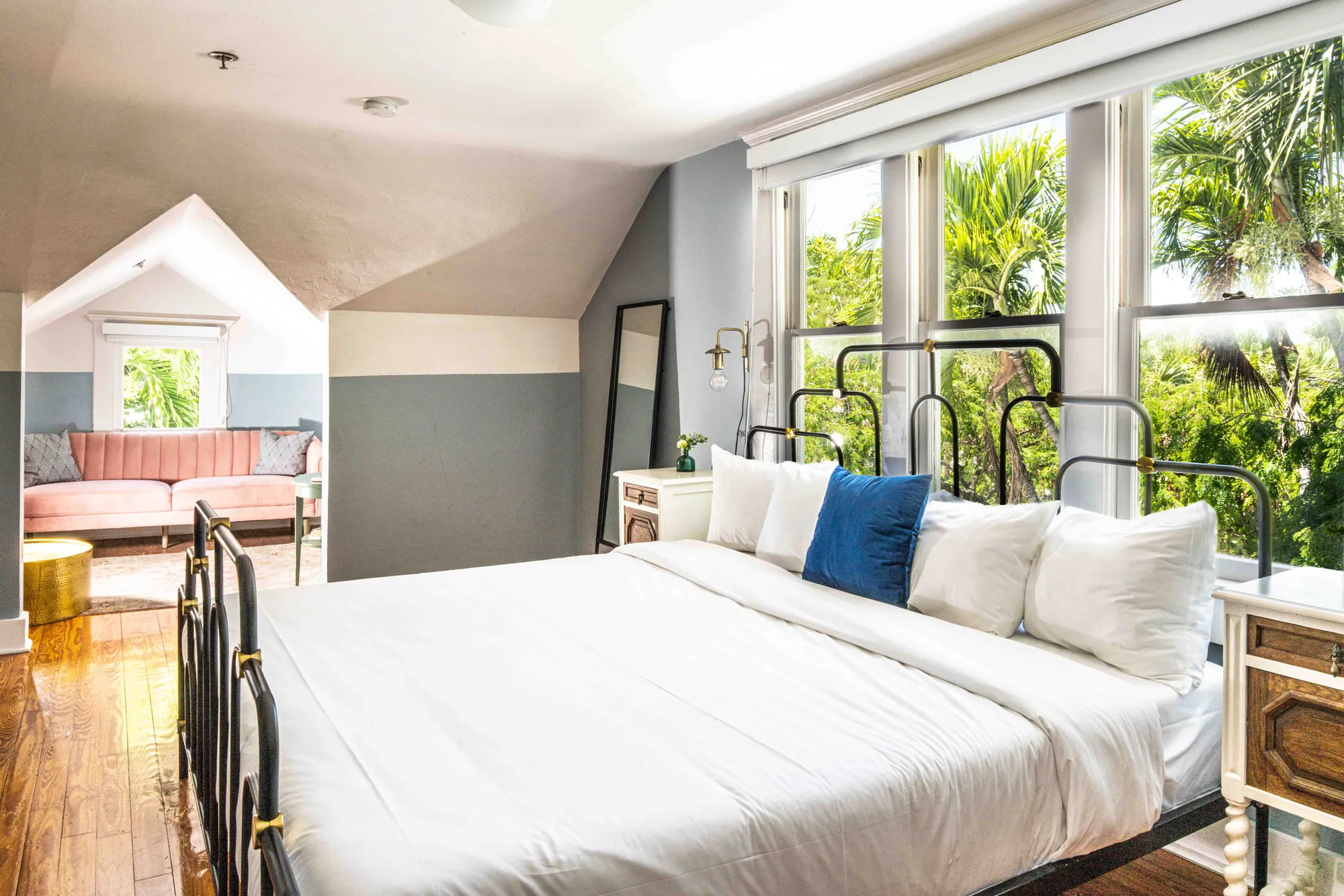 A guest room under the eaves, a wall of windows filled with palms