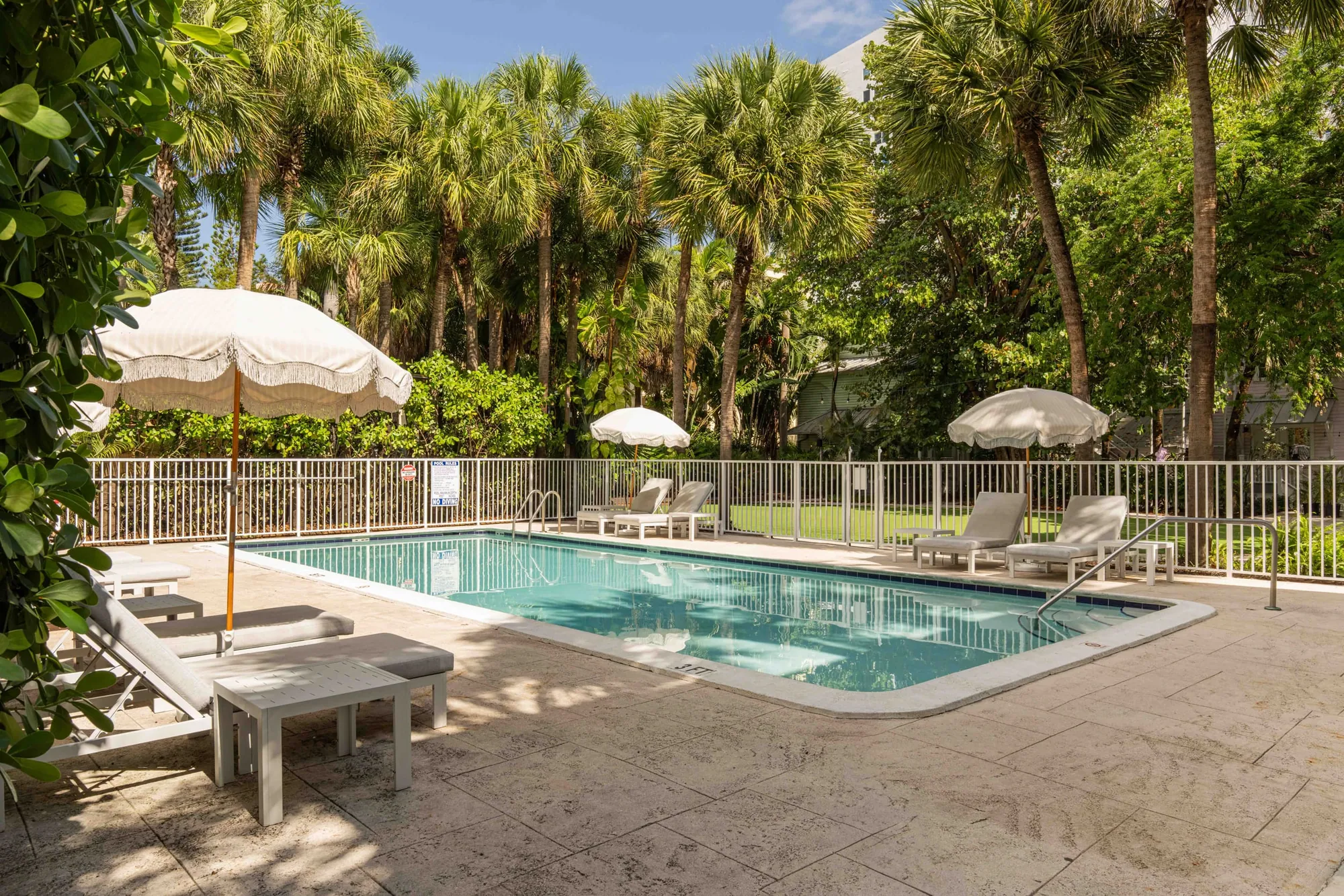 Loungers and white umbrellas along the pool in afternoon sun