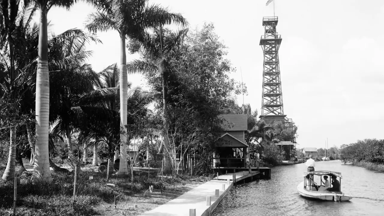 A still from the film: the Miami River in the early 1900s, palms along the bank and a launch at the dock
