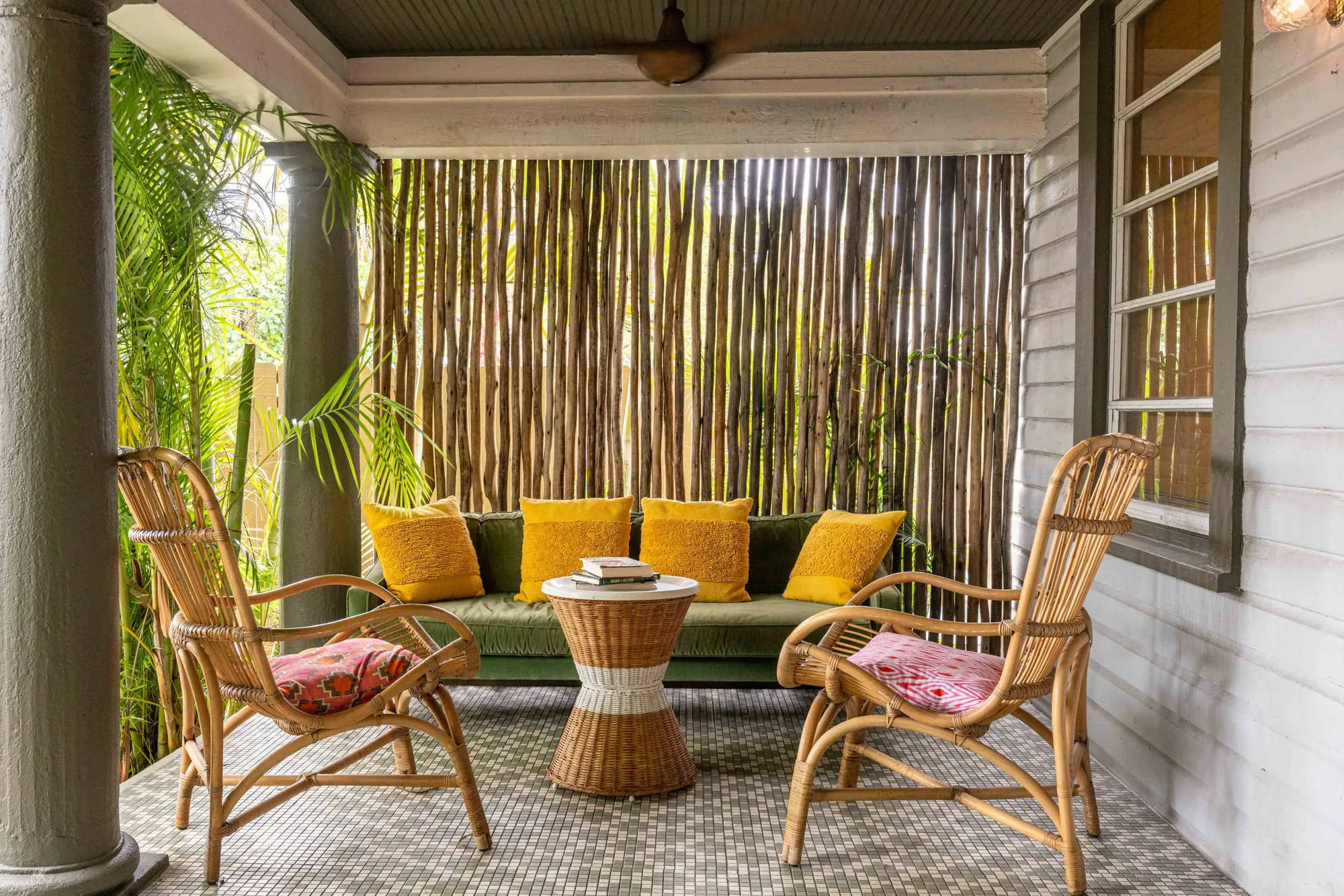 Rattan chairs and yellow cushions on the covered patio as the light goes gold