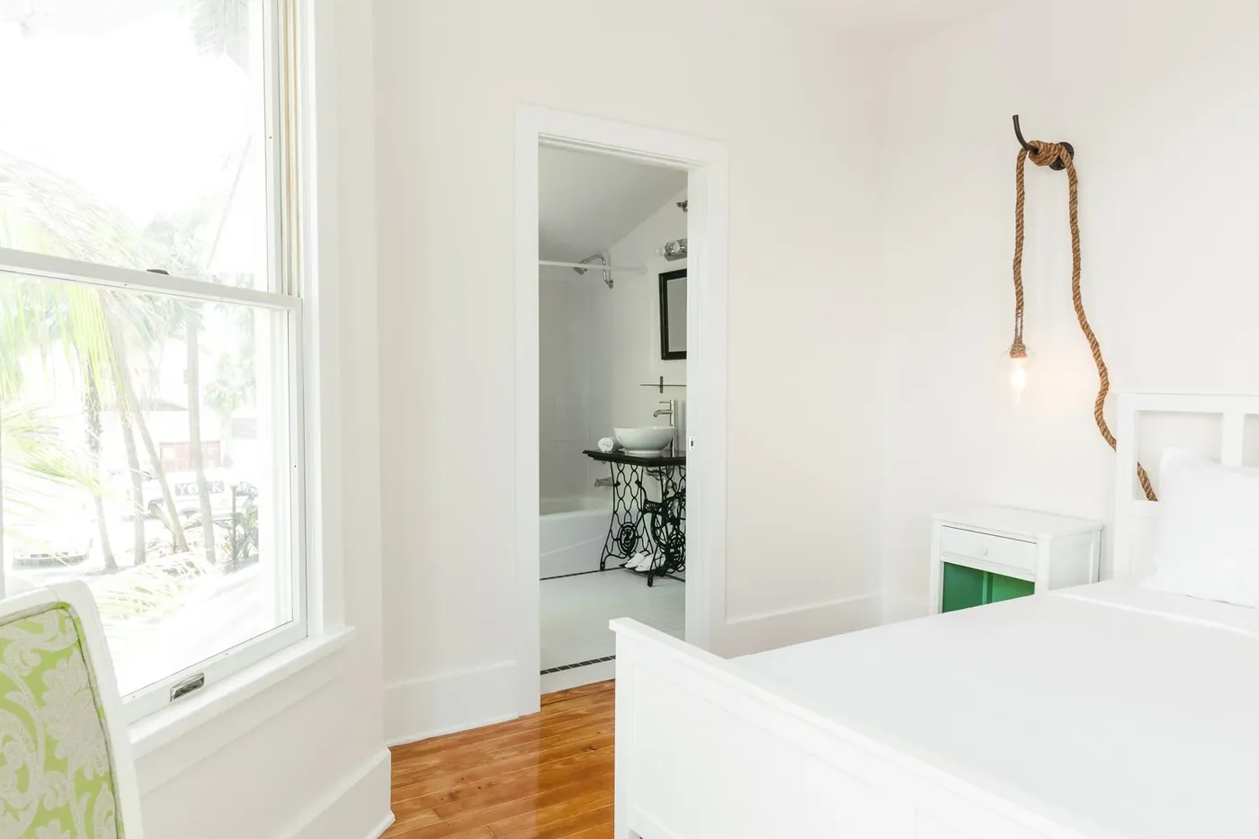 Bright white guest room with restored Dade County pine floors